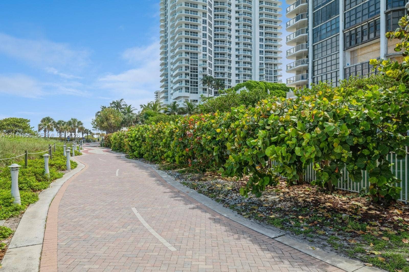 6423 Collins Avenue, #1602, Miami Beach, FL 33141 Winding brick-paver pathway bordered by mature tropical vegetation and decorative post lighting