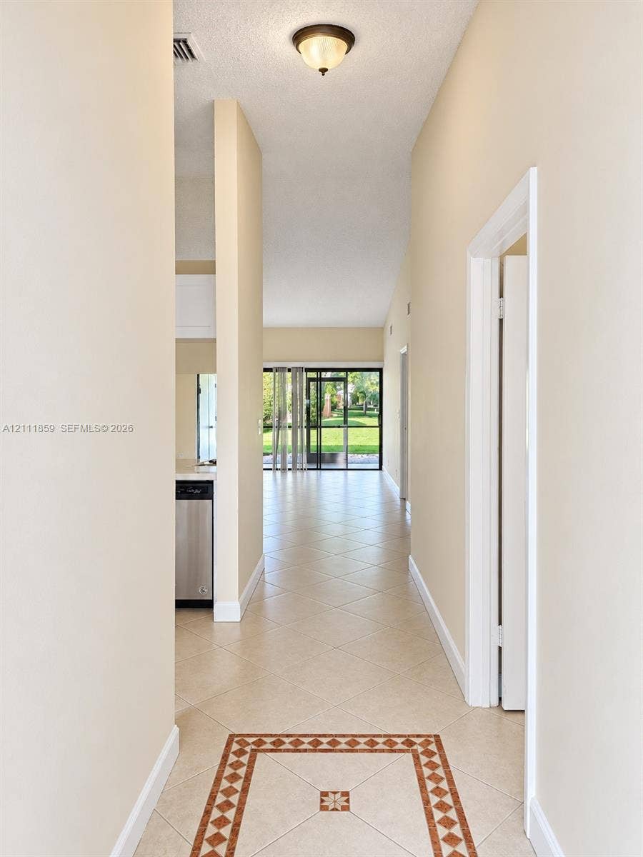 Tile flooring with decorative border inlay, vaulted ceilings, and sliding glass door access to the exterior