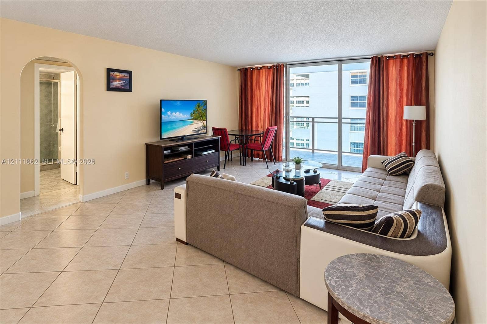 2030 S Ocean Drive, #2004, Hallandale Beach, FL 33009 Open-concept living area featuring light-toned tile flooring, an arched entryway, and large sliding glass doors providing access to a private balcony