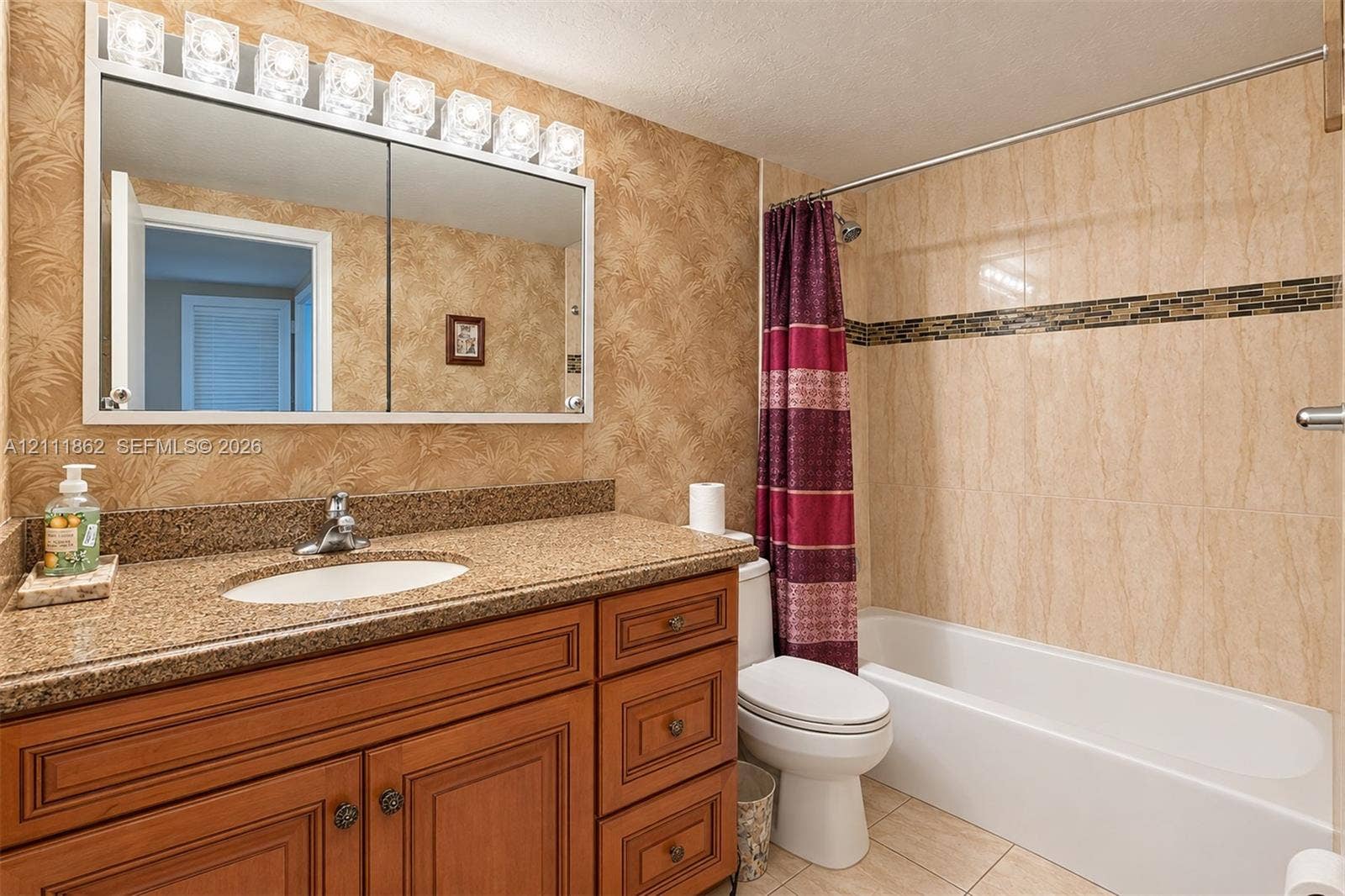 2030 S Ocean Drive, #2004, Hallandale Beach, FL 33009 Bathroom featuring wood-finish cabinetry, stone-texture countertop, integrated vanity sink, multi-light fixture, and tub-shower combination with decorative tile inlay