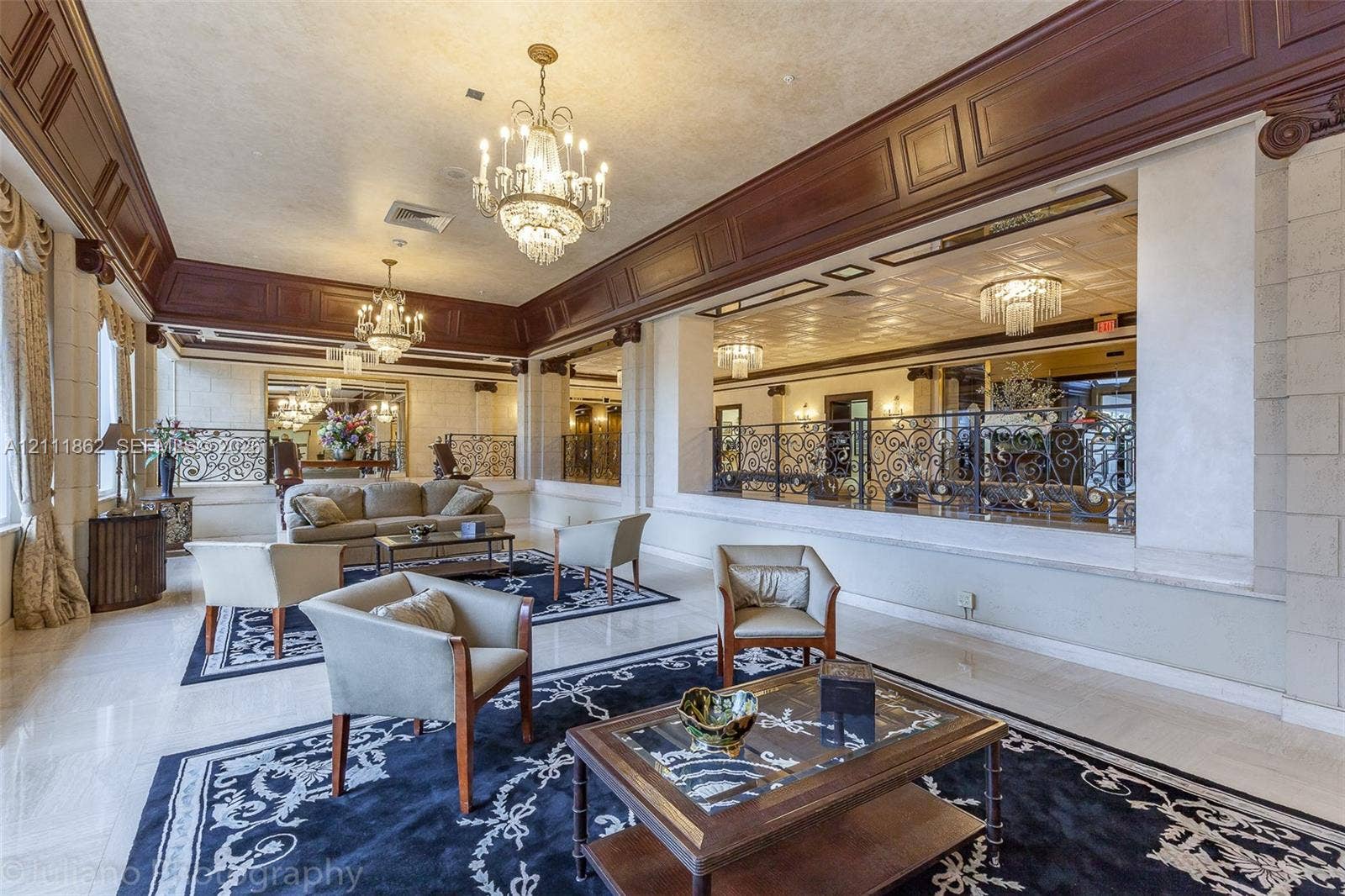 2030 S Ocean Drive, #2004, Hallandale Beach, FL 33009 Expansive interior featuring high-gloss stone flooring, ornate crystal chandeliers, intricate dark wood crown molding, and decorative wrought-iron railings