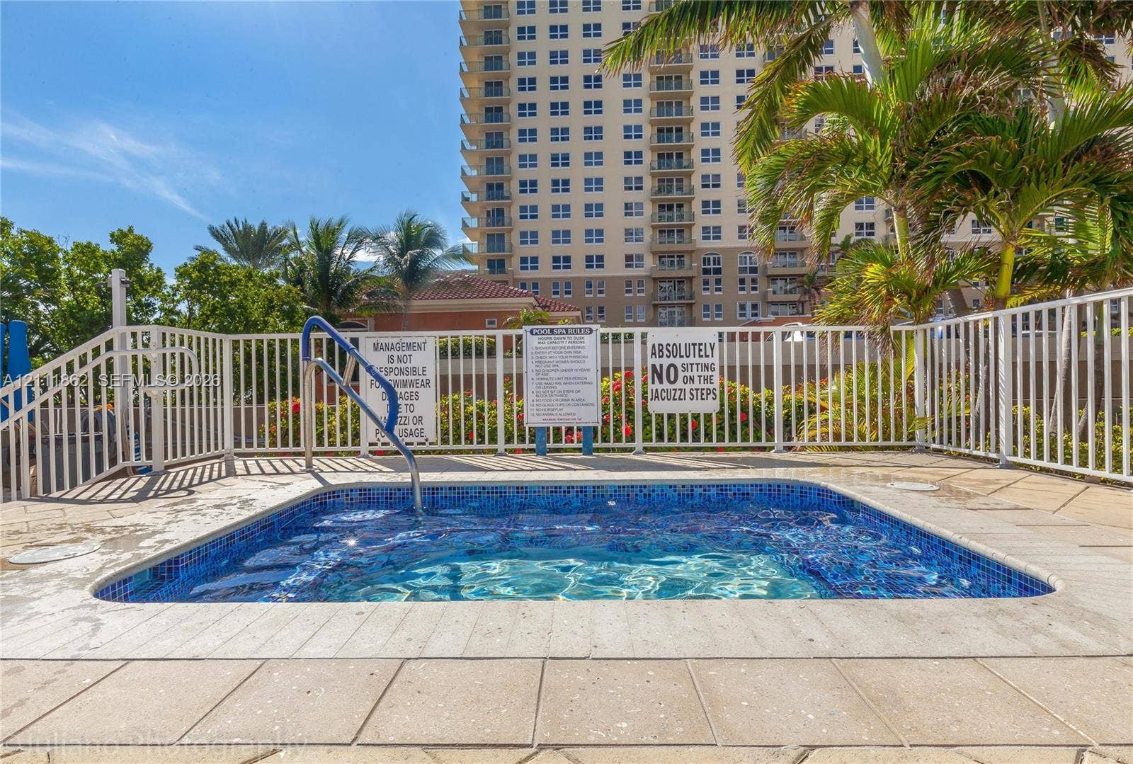 2030 S Ocean Drive, #2004, Hallandale Beach, FL 33009 In-ground spa with blue mosaic tile finish, metal handrail, and surrounding paver deck enclosed by white metal fencing