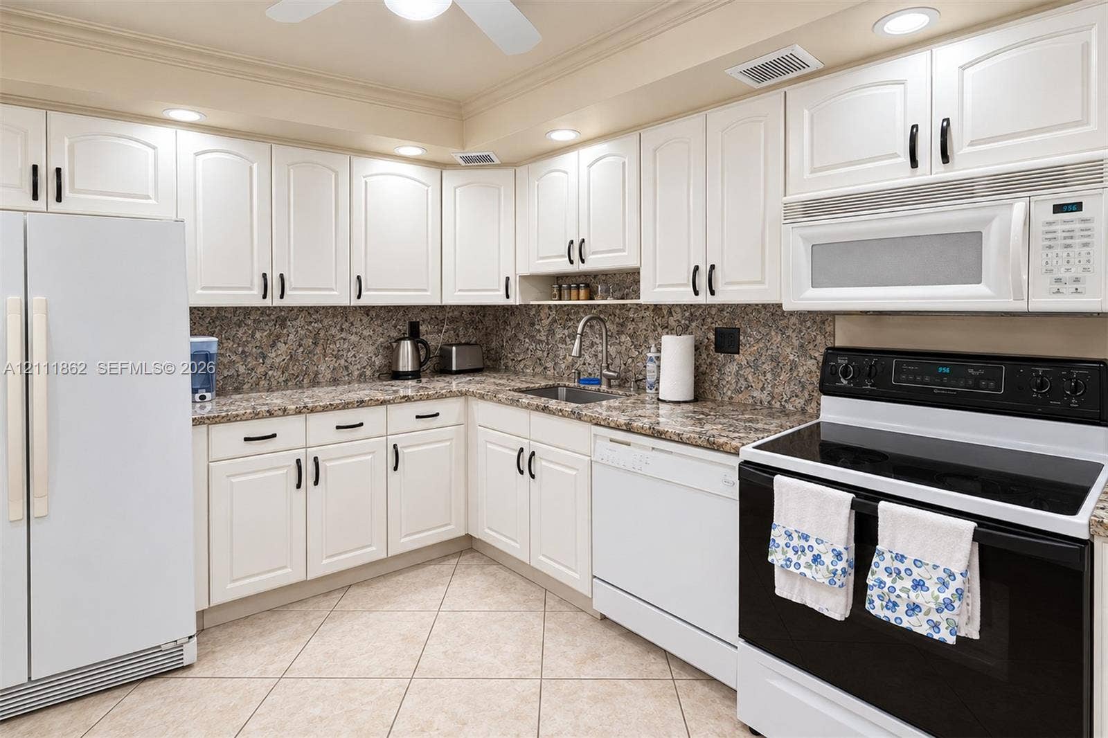 2030 S Ocean Drive, #2004, Hallandale Beach, FL 33009 Kitchen featuring white shaker-style cabinetry, stone-finish countertops, tile flooring, recessed lighting, and a stainless steel arched faucet