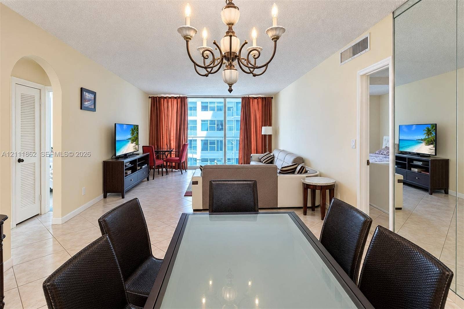 2030 S Ocean Drive, #2004, Hallandale Beach, FL 33009 Open-concept interior featuring oversized light-toned floor tiling, a traditional multi-arm chandelier, an arched doorway, and a floor-to-ceiling mirrored wall