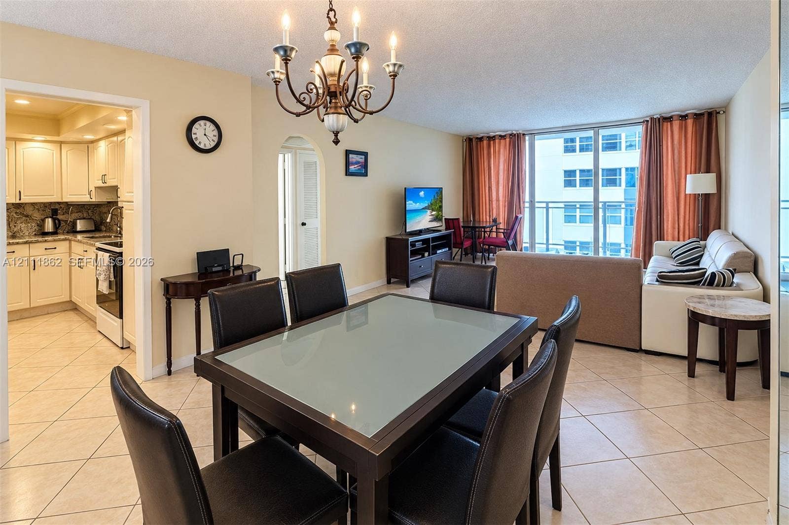 2030 S Ocean Drive, #2004, Hallandale Beach, FL 33009 Open-concept living space featuring ceramic tile flooring, arched doorways, a classic multi-arm chandelier, and glass sliding doors providing exterior access
