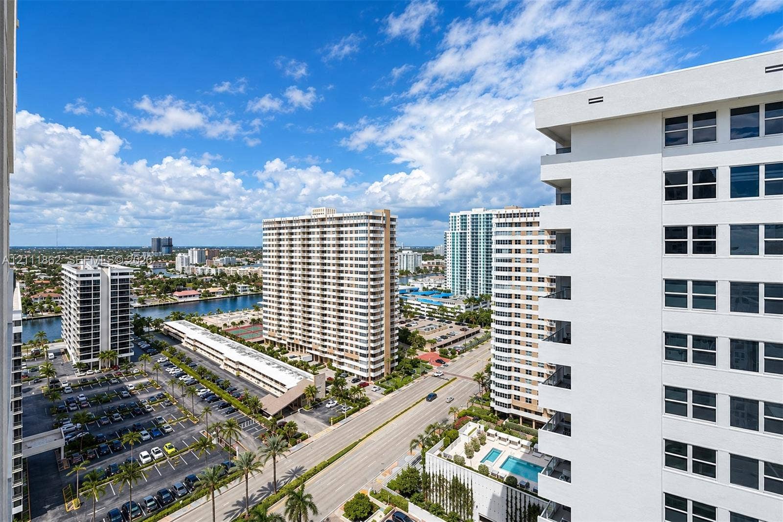 2030 S Ocean Drive, #2004, Hallandale Beach, FL 33009 Elevated exterior perspective featuring high-rise concrete architecture, palm tree landscaping, paved parking areas, and a community swimming pool