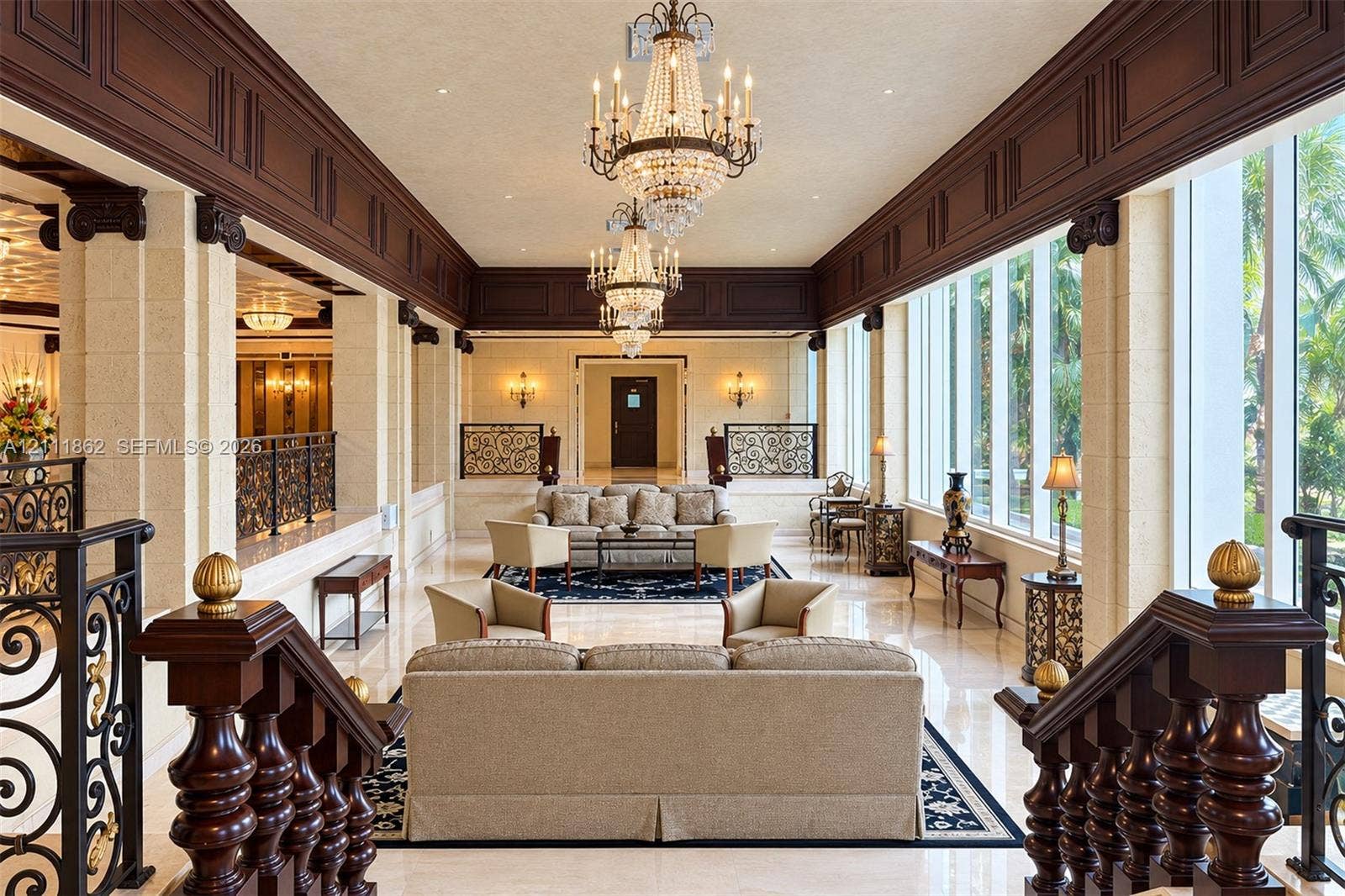 2030 S Ocean Drive, #2004, Hallandale Beach, FL 33009 Grand interior space featuring high ceilings with custom wood crown molding, dual crystal chandeliers, polished stone flooring, and expansive floor-to-ceiling windows with stone column supports