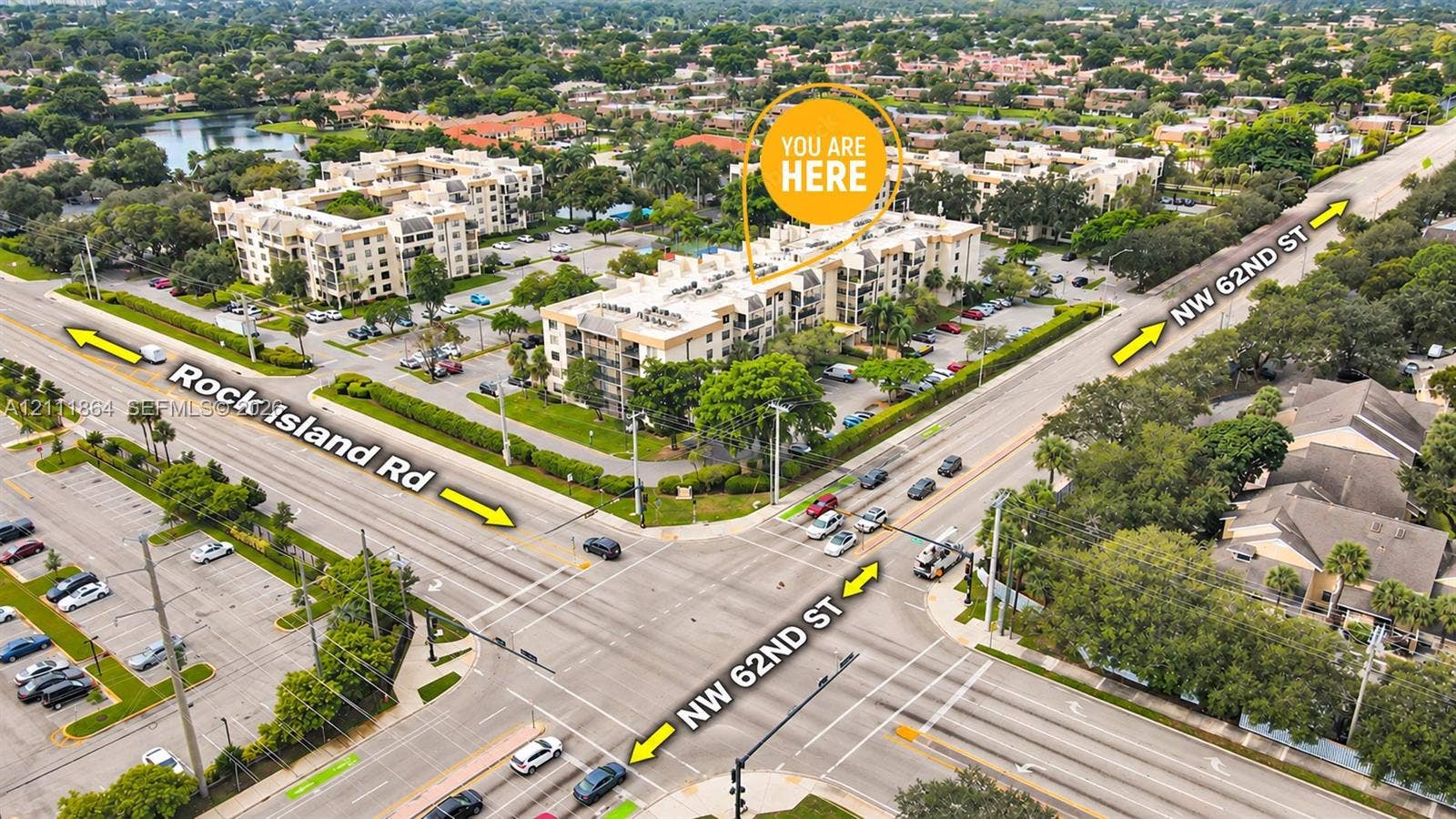 6195 Rock Island Road, #104, Tamarac, FL 33319 Aerial perspective of multi-story residential building featuring exterior surface parking, manicured perimeter landscaping, and mature canopy trees