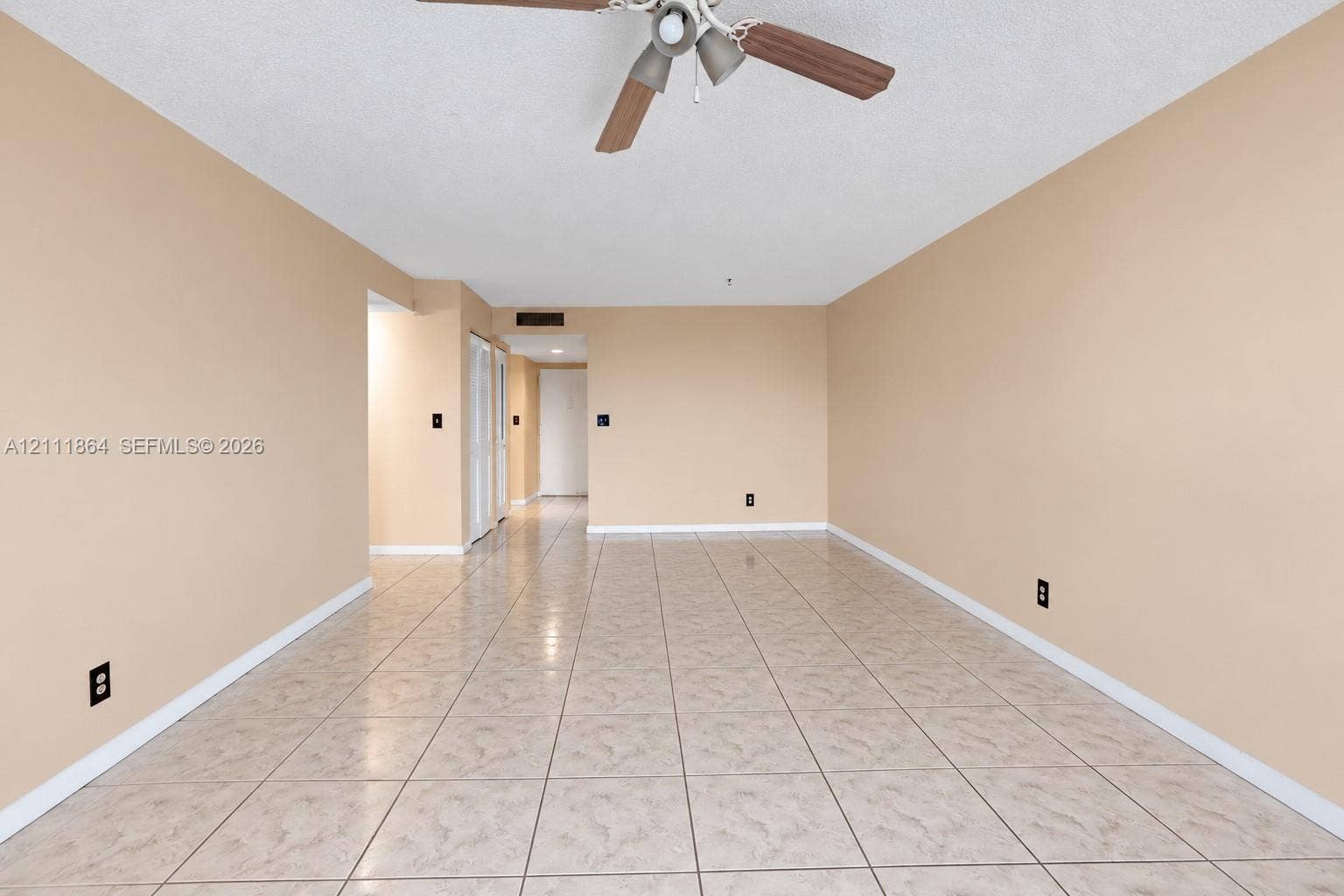 6195 Rock Island Road, #104, Tamarac, FL 33319 Spacious room featuring neutral wall paint, tiled flooring, and a ceiling-mounted light fixture with a fan
