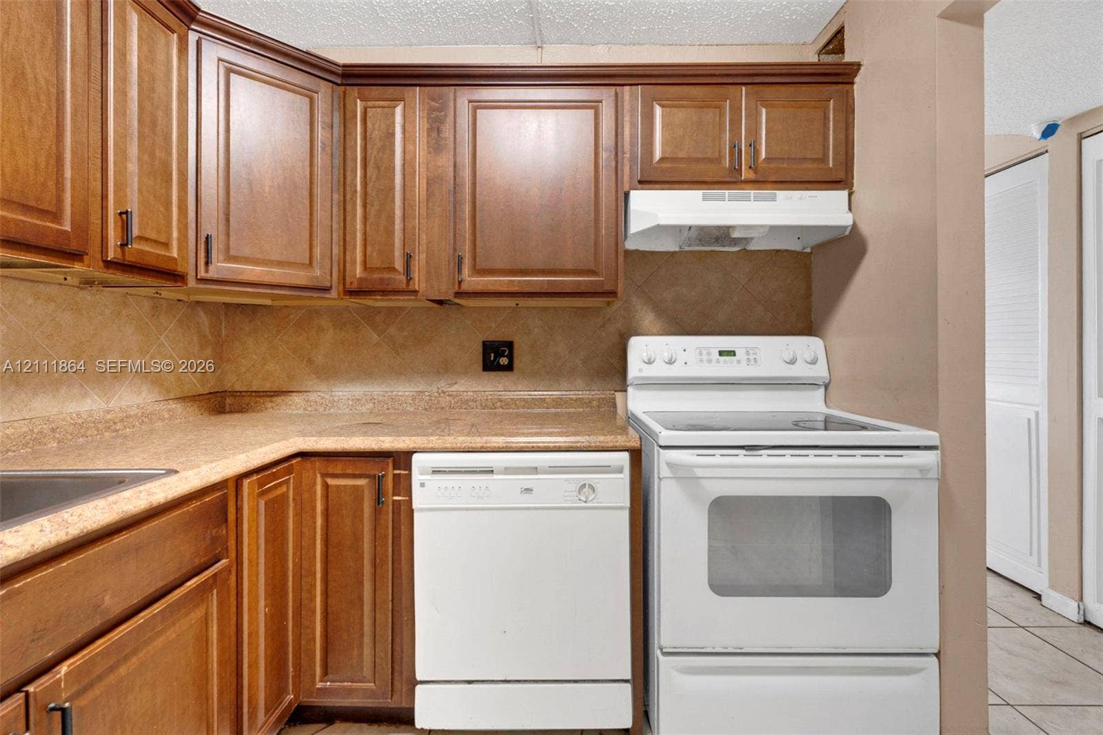 6195 Rock Island Road, #104, Tamarac, FL 33319 Kitchen featuring wood cabinetry, stone-finish countertops, tile backsplash, built-in dishwasher, and a freestanding electric range