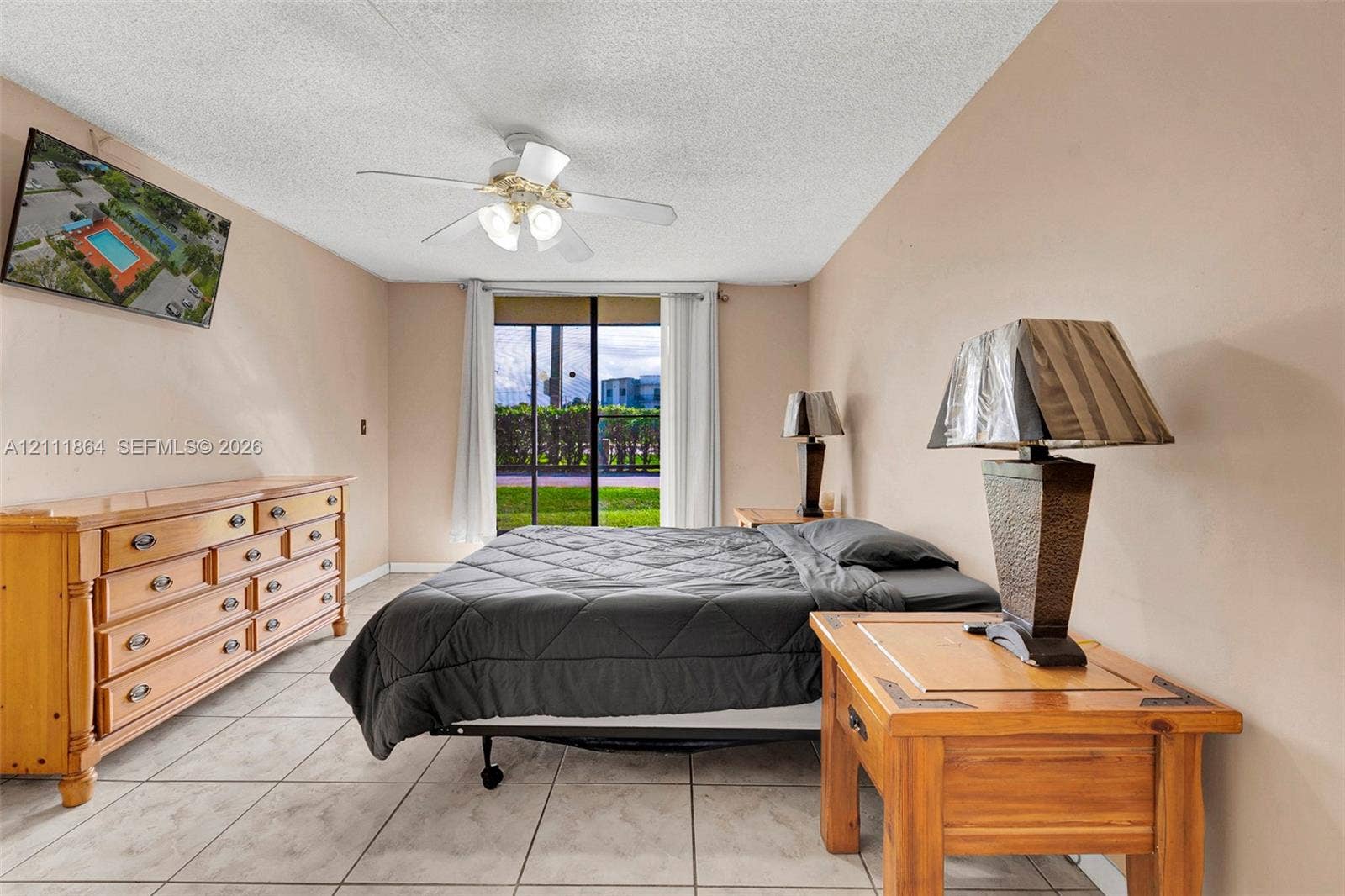 6195 Rock Island Road, #104, Tamarac, FL 33319 Bedroom featuring large-format tile flooring, a ceiling fan with integrated lighting, and a sliding glass door providing exterior access