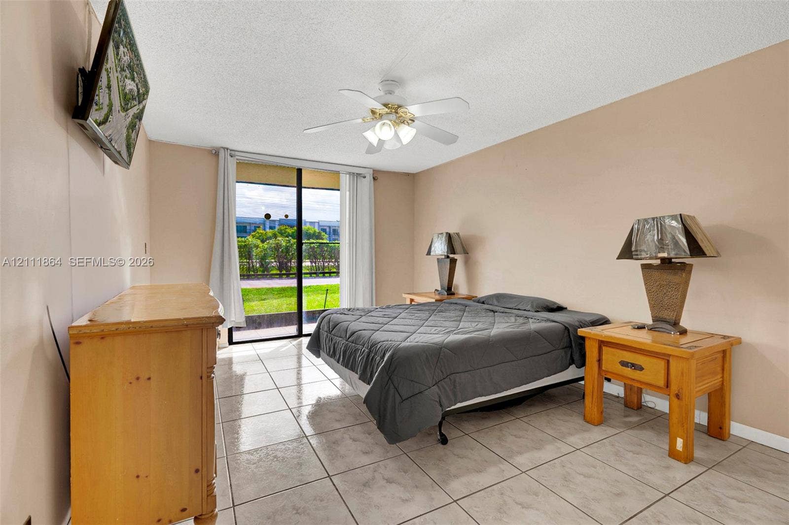 6195 Rock Island Road, #104, Tamarac, FL 33319 Neutral wall tones, ceramic tile flooring, ceiling fan with light fixture, and sliding glass door with exterior access