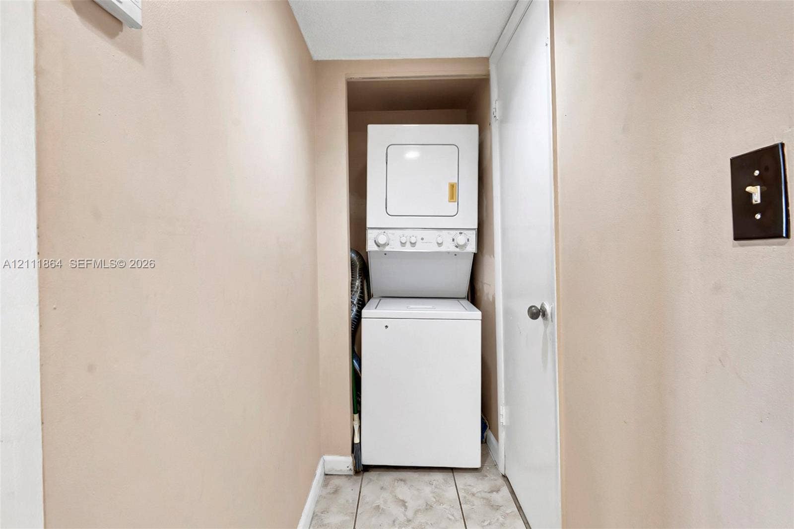 6195 Rock Island Road, #104, Tamarac, FL 33319 Utility closet featuring a stacked washer and dryer unit and tile flooring