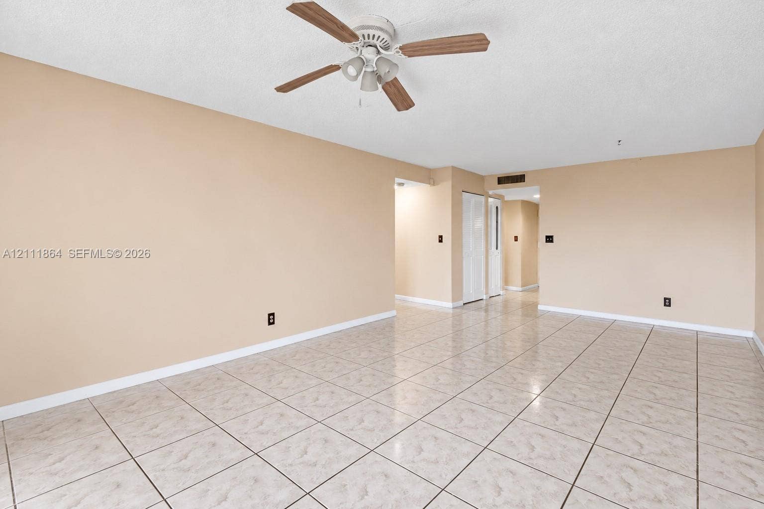 6195 Rock Island Road, #104, Tamarac, FL 33319 Open interior space featuring neutral wall tones, large-format tile flooring, and a ceiling fan with integrated lighting