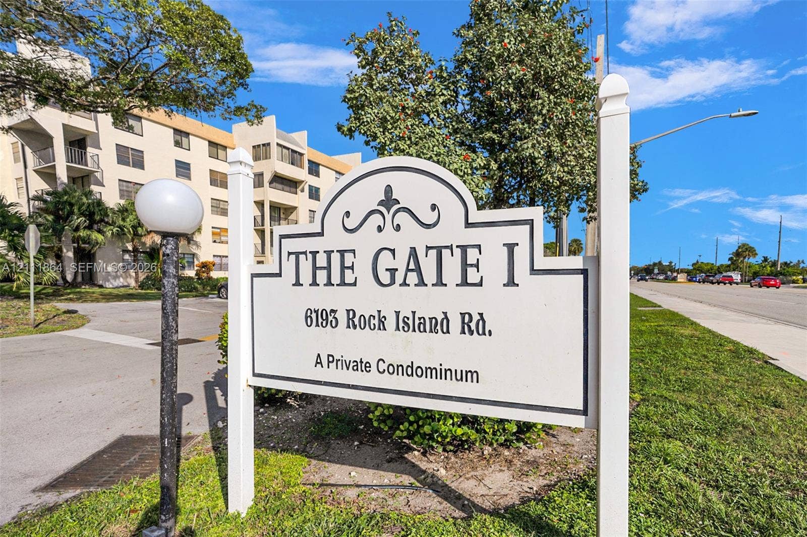 6195 Rock Island Road, #104, Tamarac, FL 33319 Monument signage for The Gate I condominium featuring an arched, scroll-work design on a post-and-panel frame