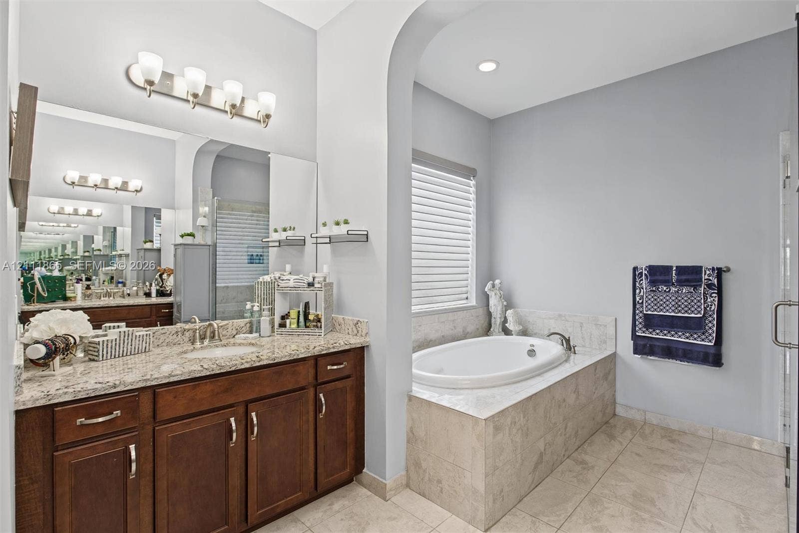 1034 SW 113th Avenue, Pembroke Pines, FL 33025 Master Bathroom featuring rich wood cabinetry and stone countertop + soaking tub.