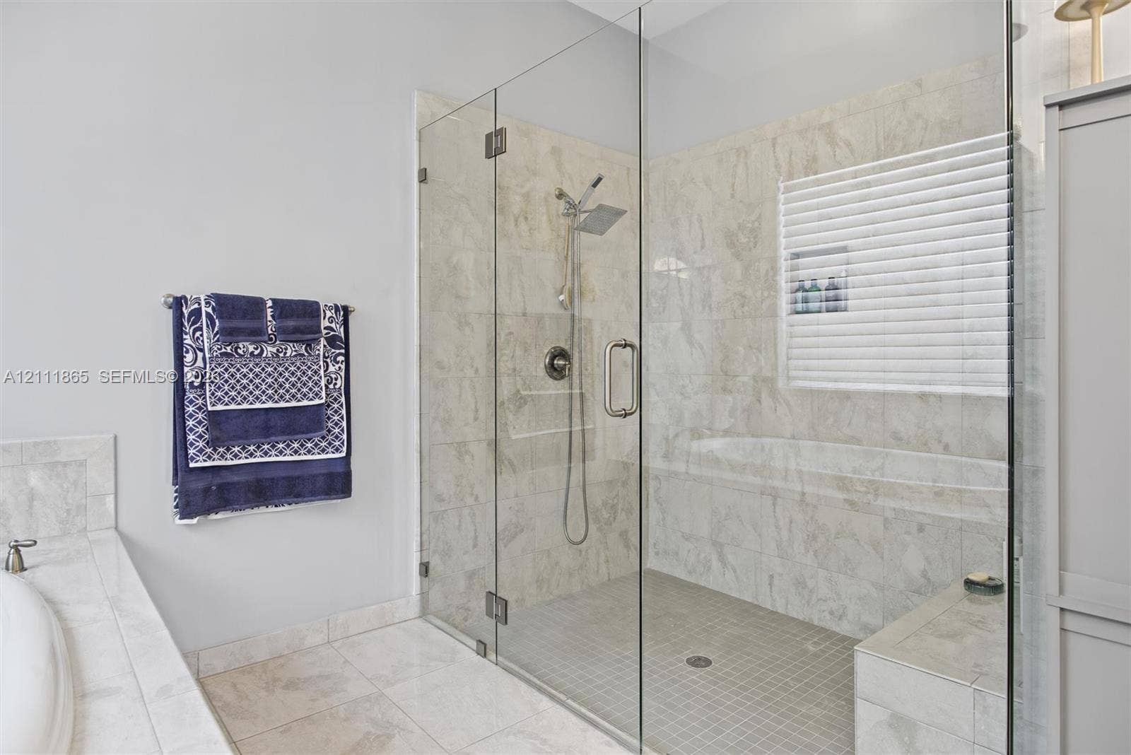 1034 SW 113th Avenue, Pembroke Pines, FL 33025 Large master walk-in shower with frameless glass enclosure, natural stone wall tile and integrated bench.