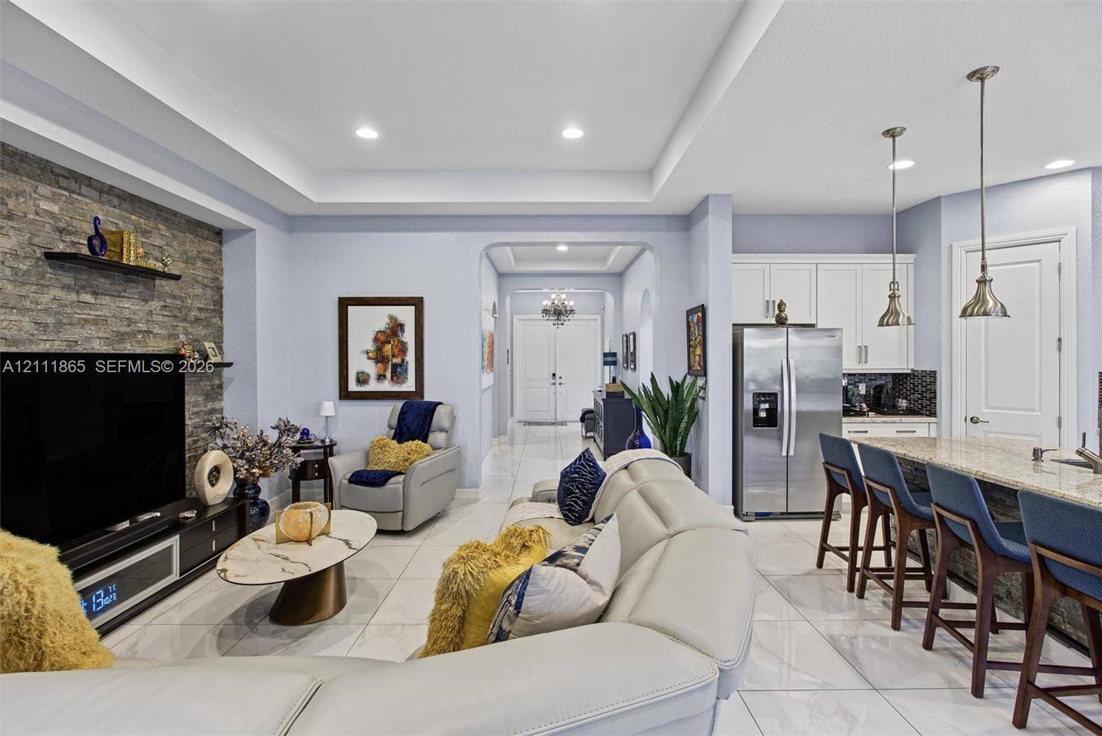 1034 SW 113th Avenue, Pembroke Pines, FL 33025 Living space featuring a stone accent wall & recessed tray ceiling.