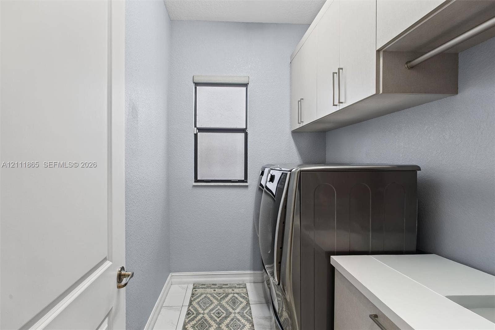 1034 SW 113th Avenue, Pembroke Pines, FL 33025 Spacious Laundry featuring custom cabinetry, a solid-surface countertop with built-in hanging rod.