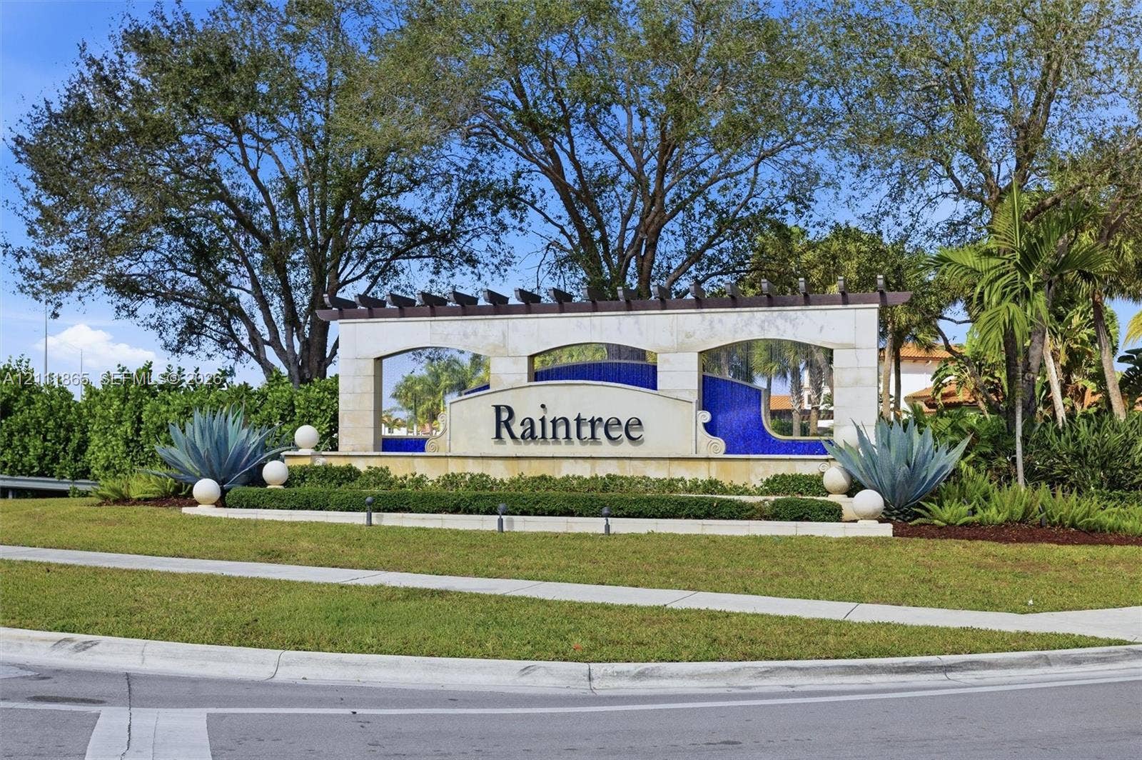 1034 SW 113th Avenue, Pembroke Pines, FL 33025 Raintree community entrance monument featuring stone masonry, a decorative wooden pergola, blue tile accents, and professional landscaping
