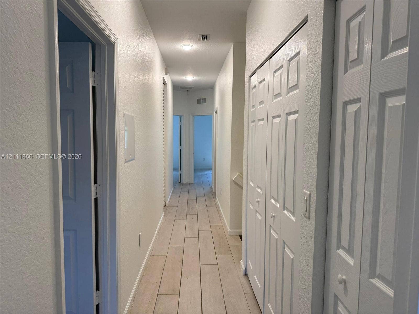 Hallway featuring wood-finish flooring, recessed ceiling lighting, and multiple bi-fold closet doors