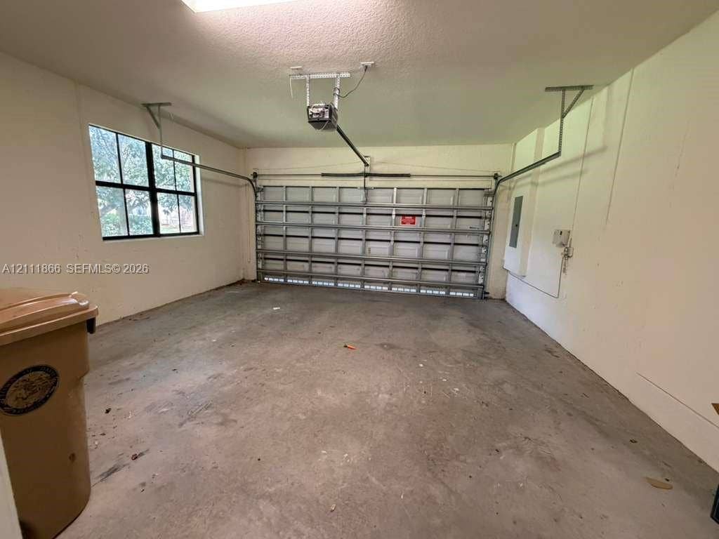 Attached garage featuring a multi-panel overhead door, concrete flooring, and a grid-pane window
