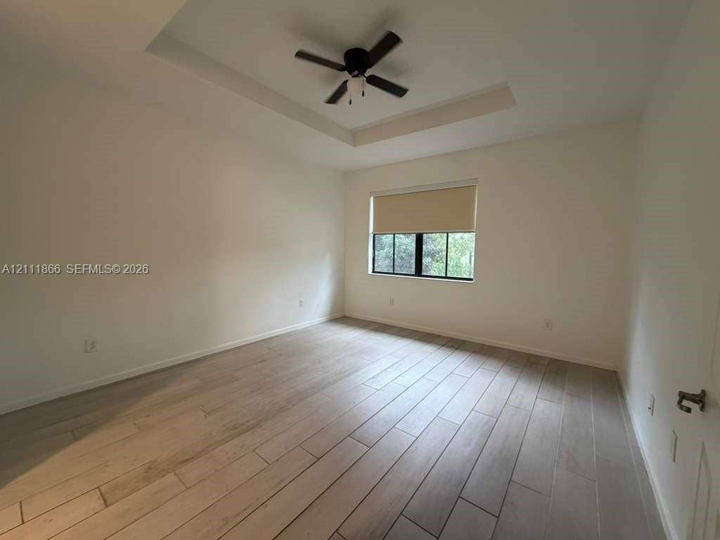 Tray ceiling, wood-finish tile flooring, and integrated ceiling fan