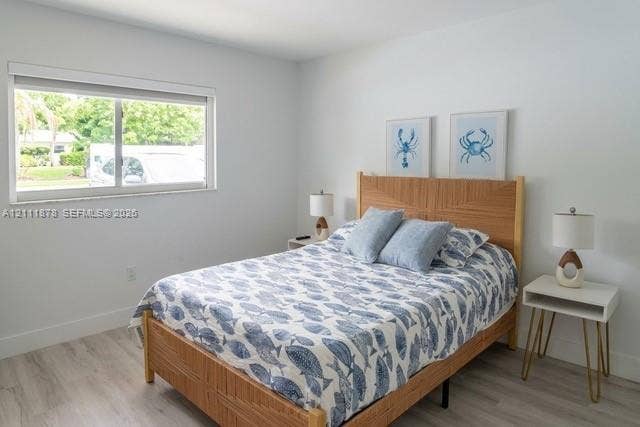 201 Galen Drive, #110, Key Biscayne, FL 33149 Bedroom interior featuring wood-finish flooring, a neutral color palette, and a large sliding window with a minimalist blind