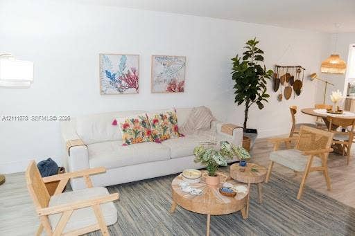 201 Galen Drive, #110, Key Biscayne, FL 33149 Open-concept area featuring neutral wall tones, wood-finish flooring, and two woven pendant light fixtures