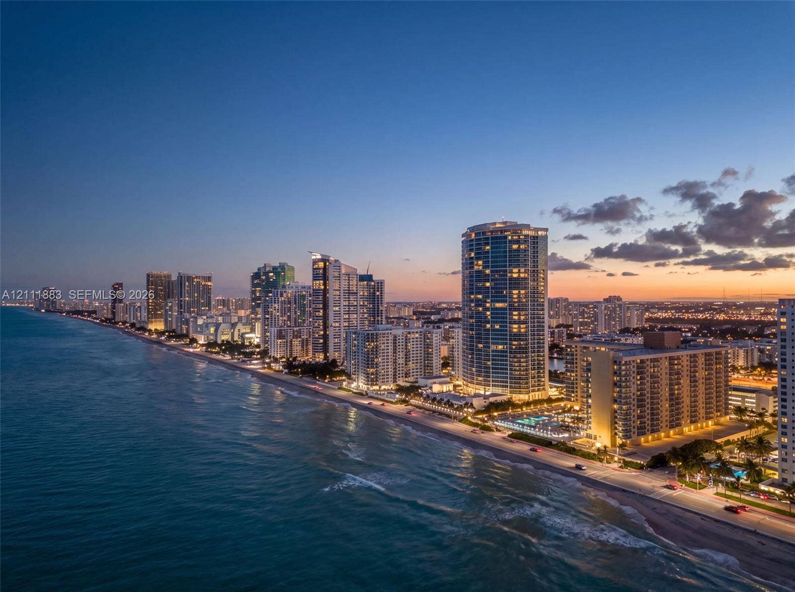 Coastal high-rise buildings situated directly along the shoreline with sandy beach access and expansive ocean horizons