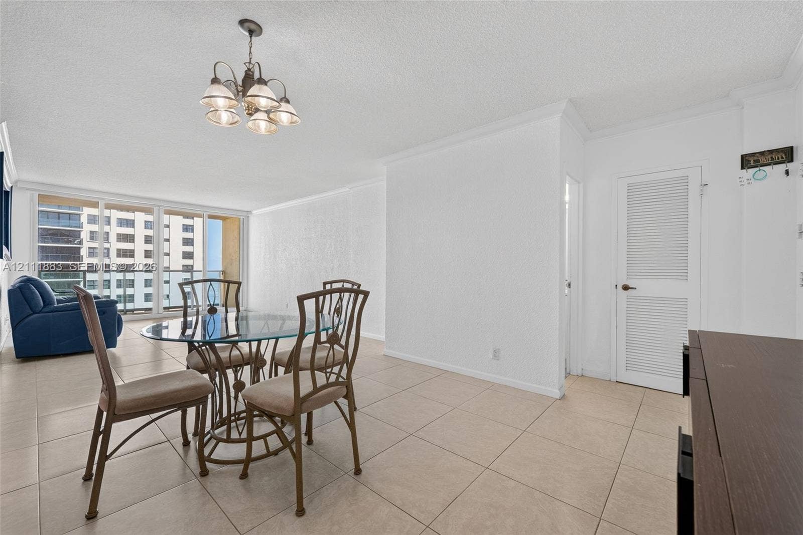 Large-format floor tile, multi-pane floor-to-ceiling windows, brushed nickel five-light chandelier, and louvered-panel closet door