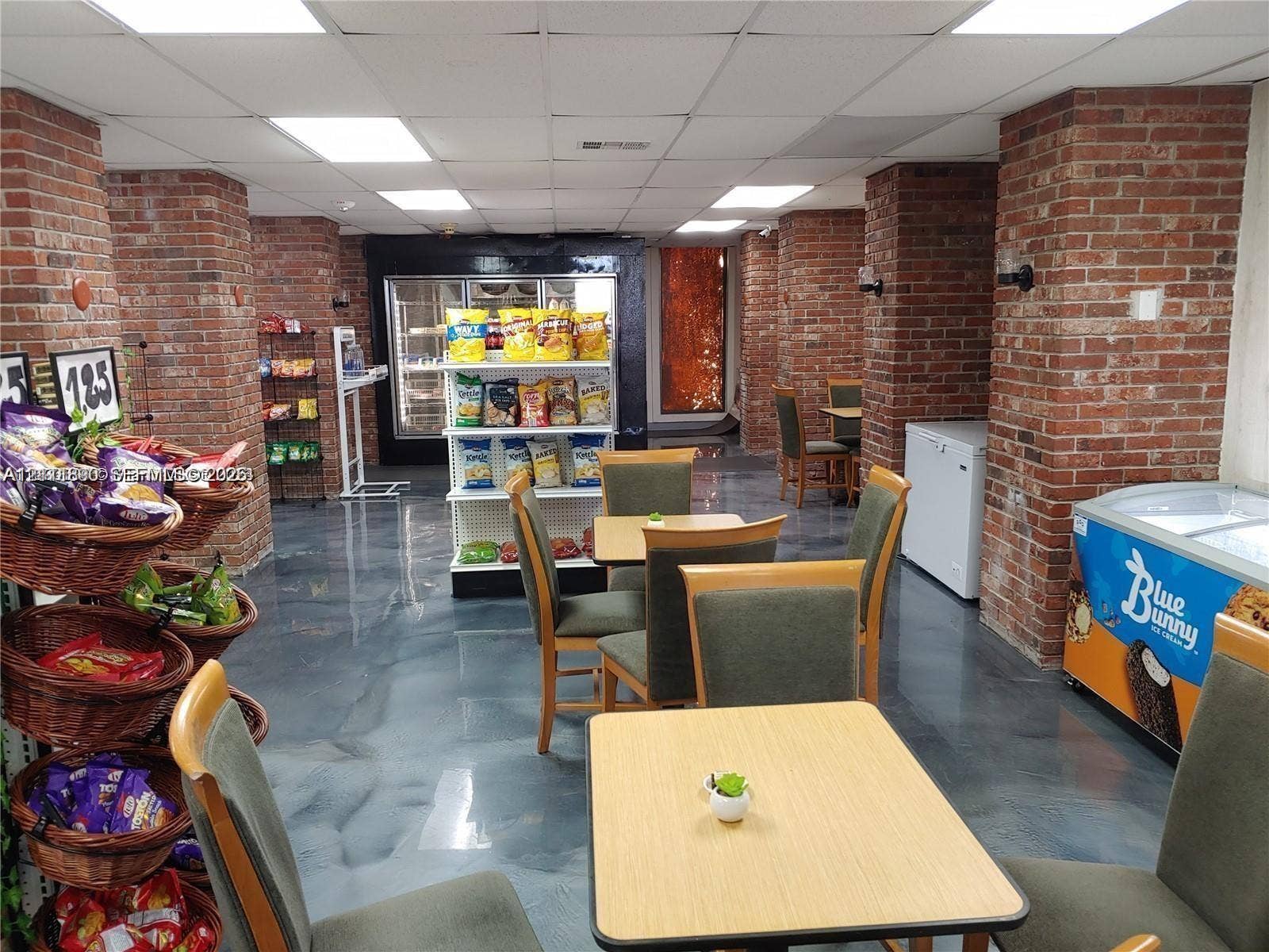 Exposed brick columns, finished metallic-epoxy flooring, and suspended grid ceiling