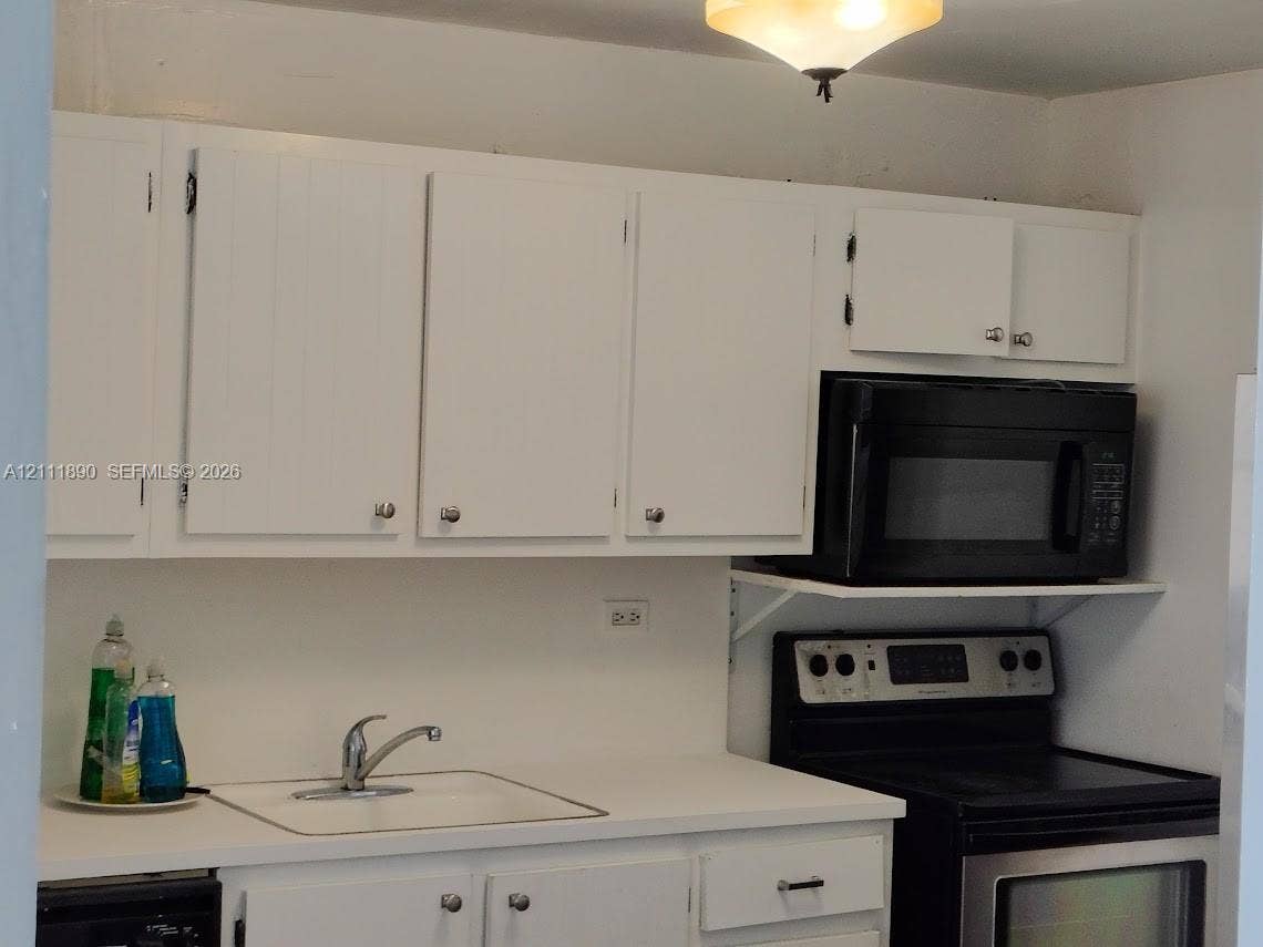 Kitchen featuring white cabinetry, integrated sink, built-in microwave, and stainless steel range