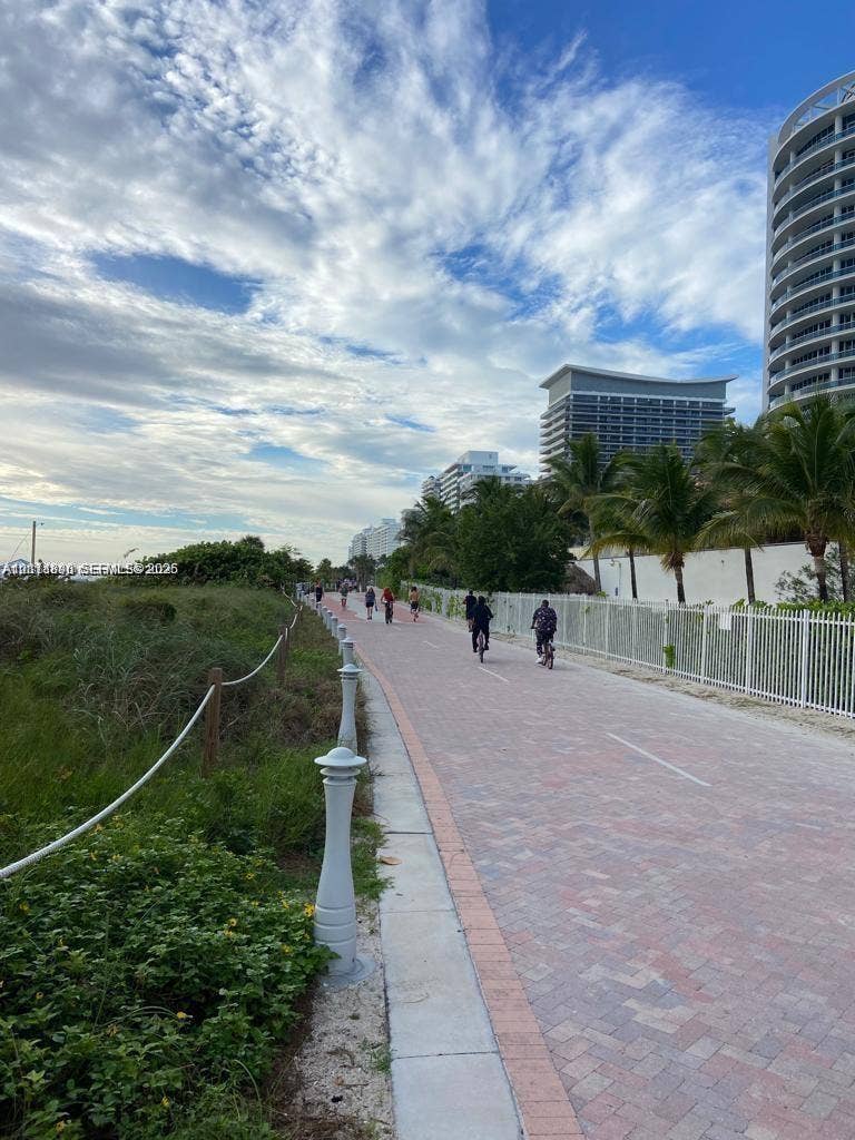 Paved multi-use path featuring decorative bollards, coastal landscaping, and high-rise architecture