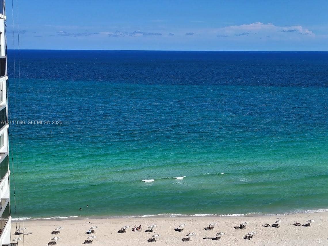 High-rise exterior featuring a direct oceanfront position, sand beach access, and panoramic coastal horizon