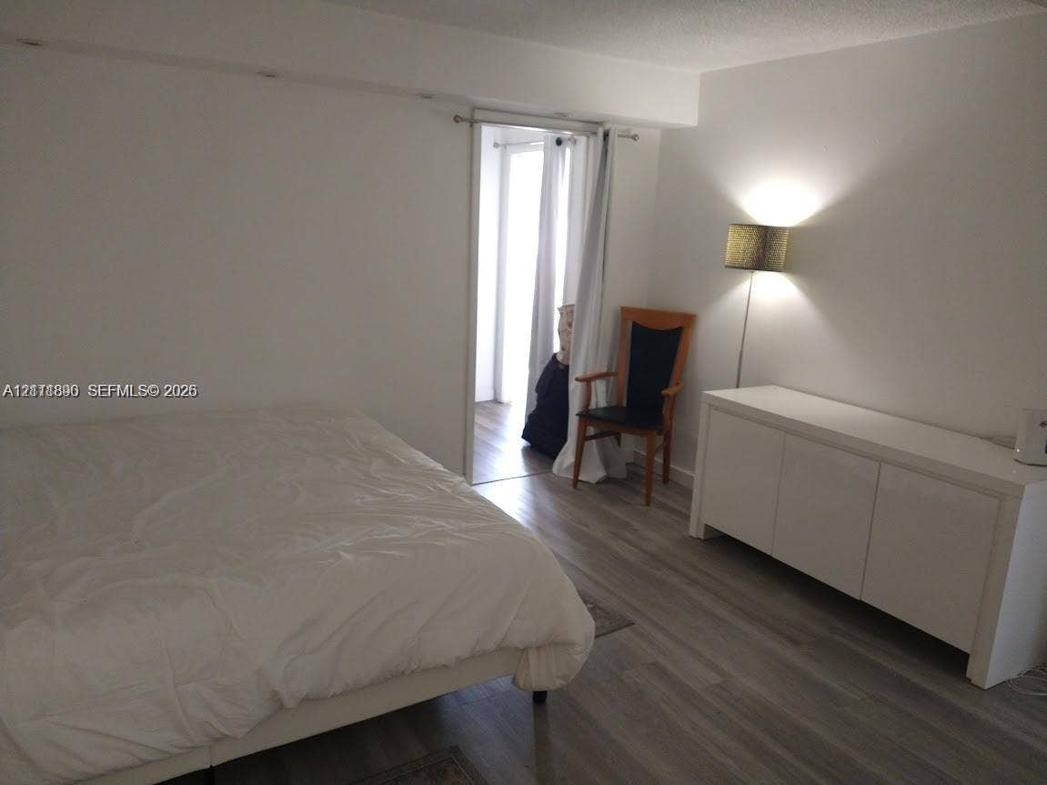 Neutral interior featuring wood-finish flooring and a doorway leading to a secondary space