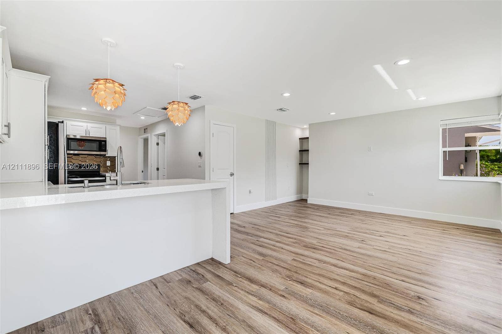 Kitchen featuring a waterfall-edge countertop, wood-finish flooring, recessed lighting, and textured pendant fixtures
