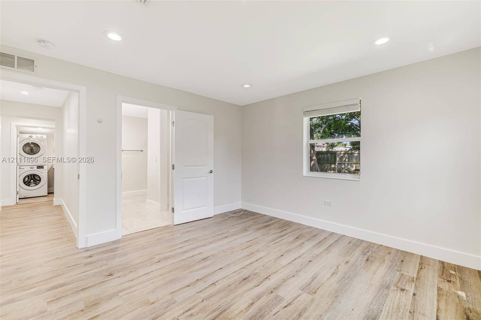 Neutral-toned interior featuring wood-finish flooring, recessed lighting, and a single-hung window with a roller shade
