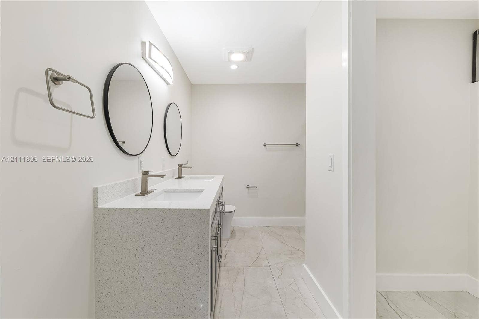 Double vanity featuring a light-toned countertop, rectangular undermount sinks, and wall-mounted circular mirrors