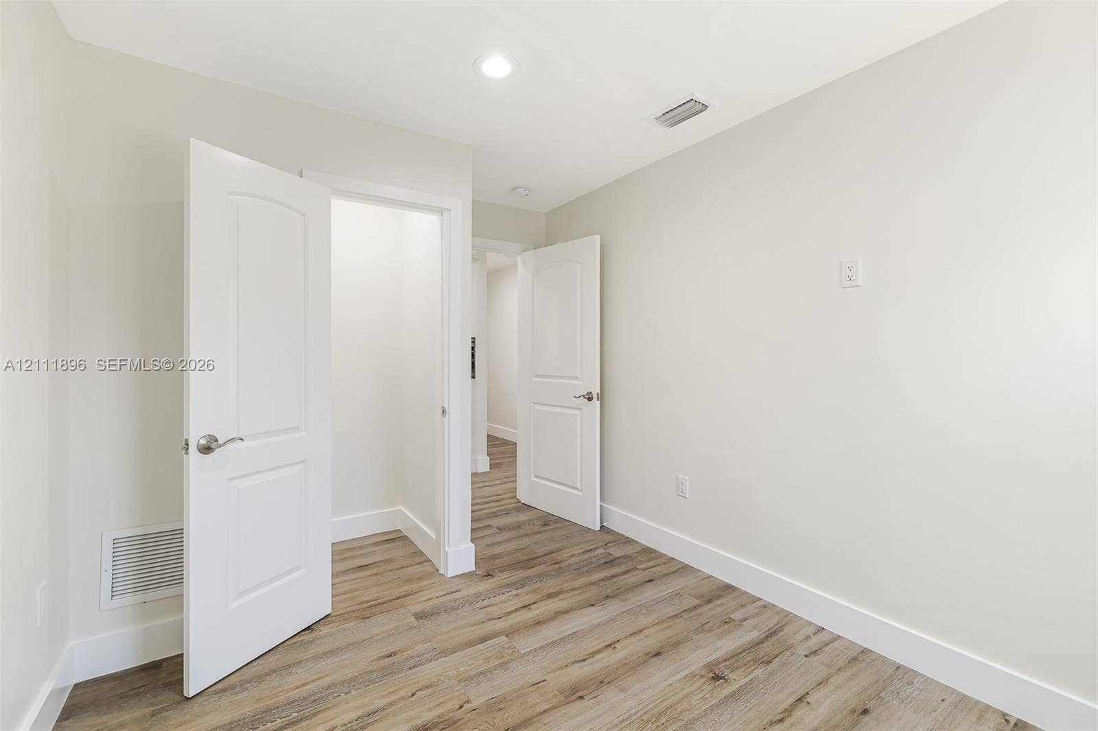 Wood-finish flooring, neutral wall tones, recessed lighting, and white paneled doors
