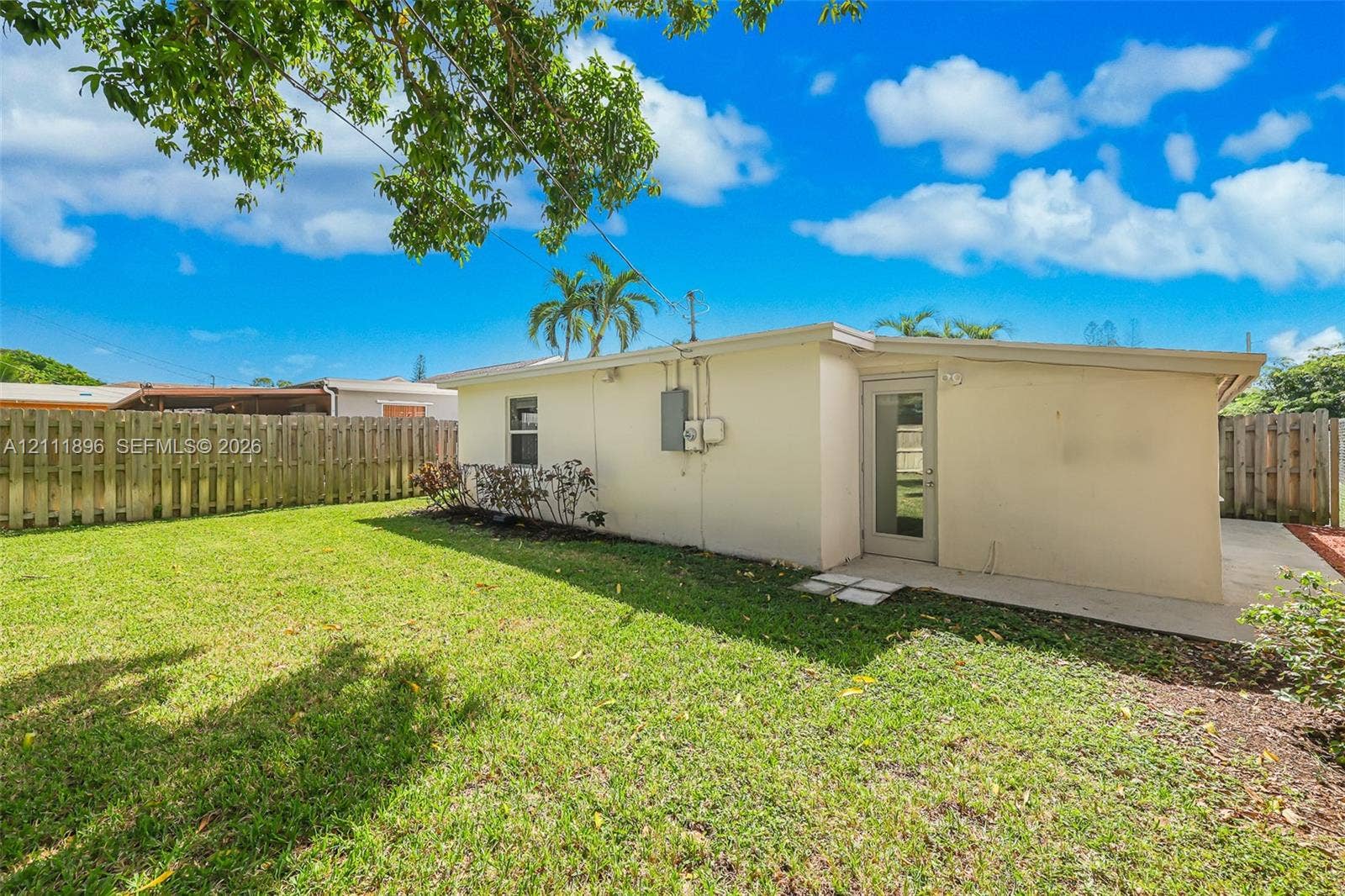 Private backyard featuring a manicured lawn, concrete patio, and wood privacy fencing