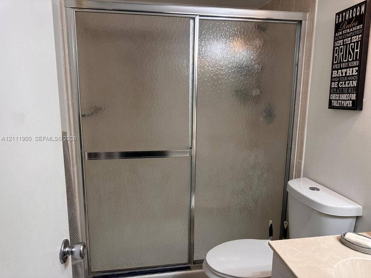711 N Pine Island Road, #402, Plantation, Plantation, FL 33324 Shower enclosure featuring chrome-finish sliding doors and textured glass, tile surround, and a standard-height toilet