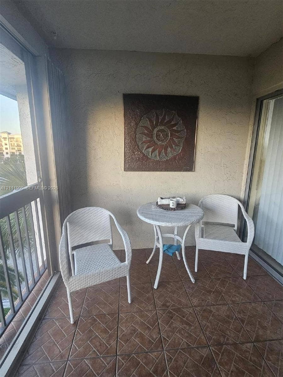 711 N Pine Island Road, #402, Plantation, Plantation, FL 33324 Covered balcony featuring textured walls, metal railing, and ceramic tile flooring