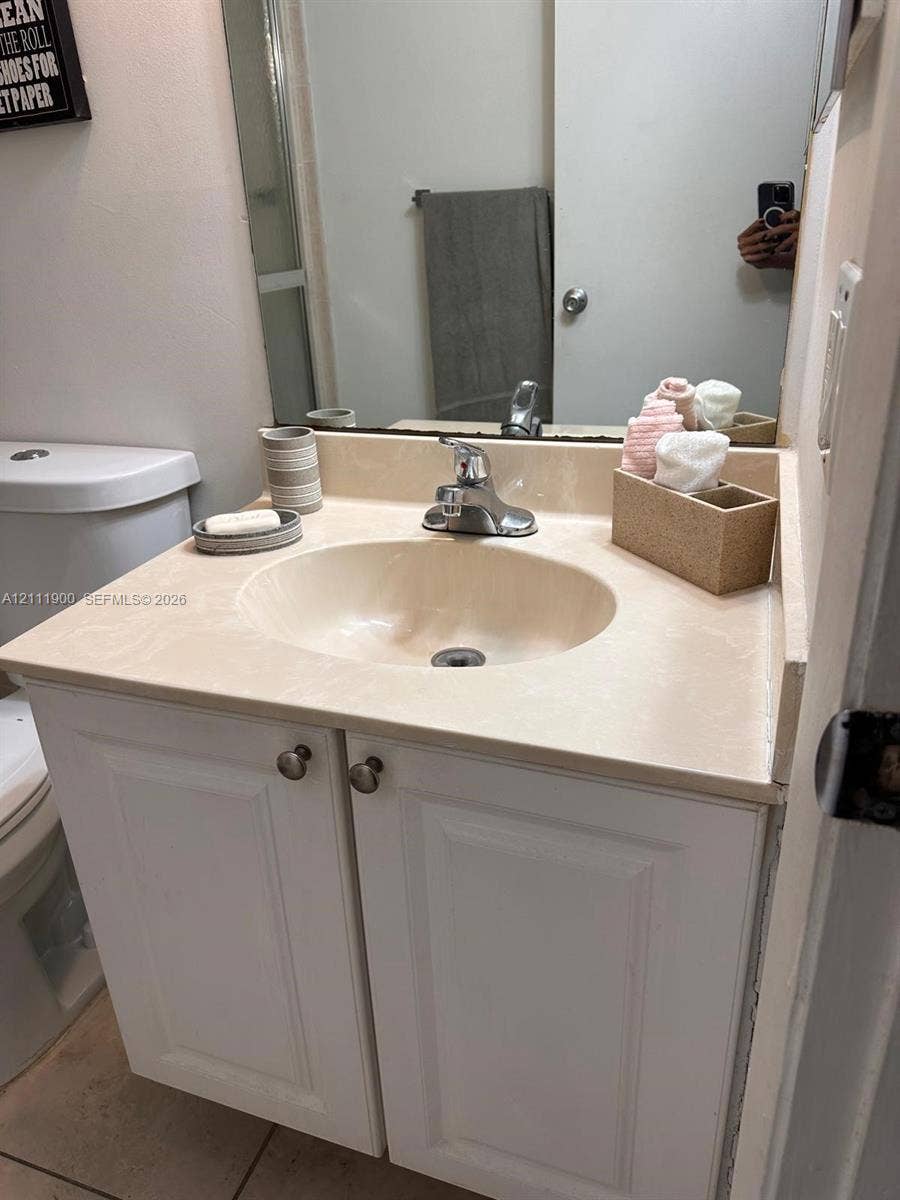 711 N Pine Island Road, #402, Plantation, Plantation, FL 33324 Bathroom vanity featuring white cabinetry, a molded countertop with integrated basin, polished metal faucet, and wall-mounted mirror