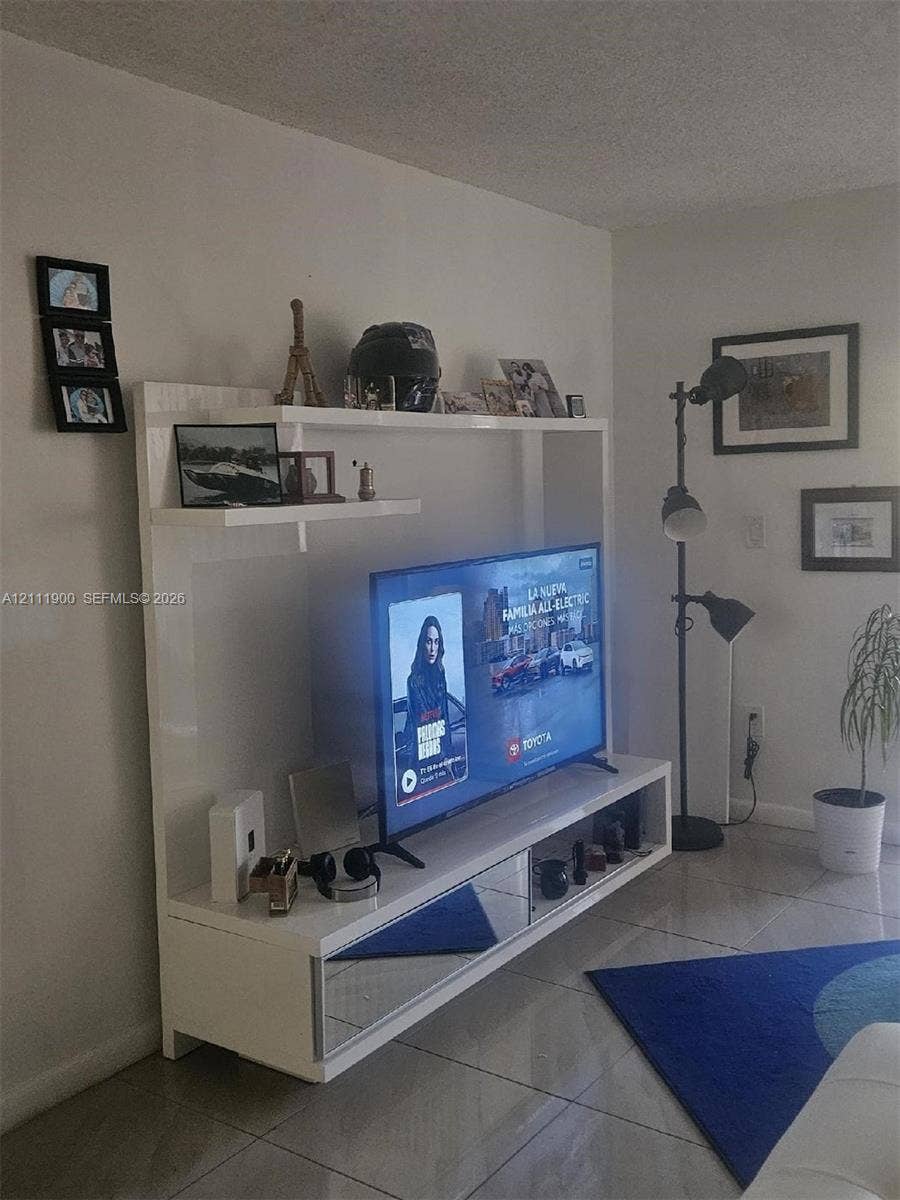711 N Pine Island Road, #402, Plantation, Plantation, FL 33324 Built-in white entertainment center featuring a high-gloss finish, mirrored drawer fronts, and open display shelving, paired with tile flooring