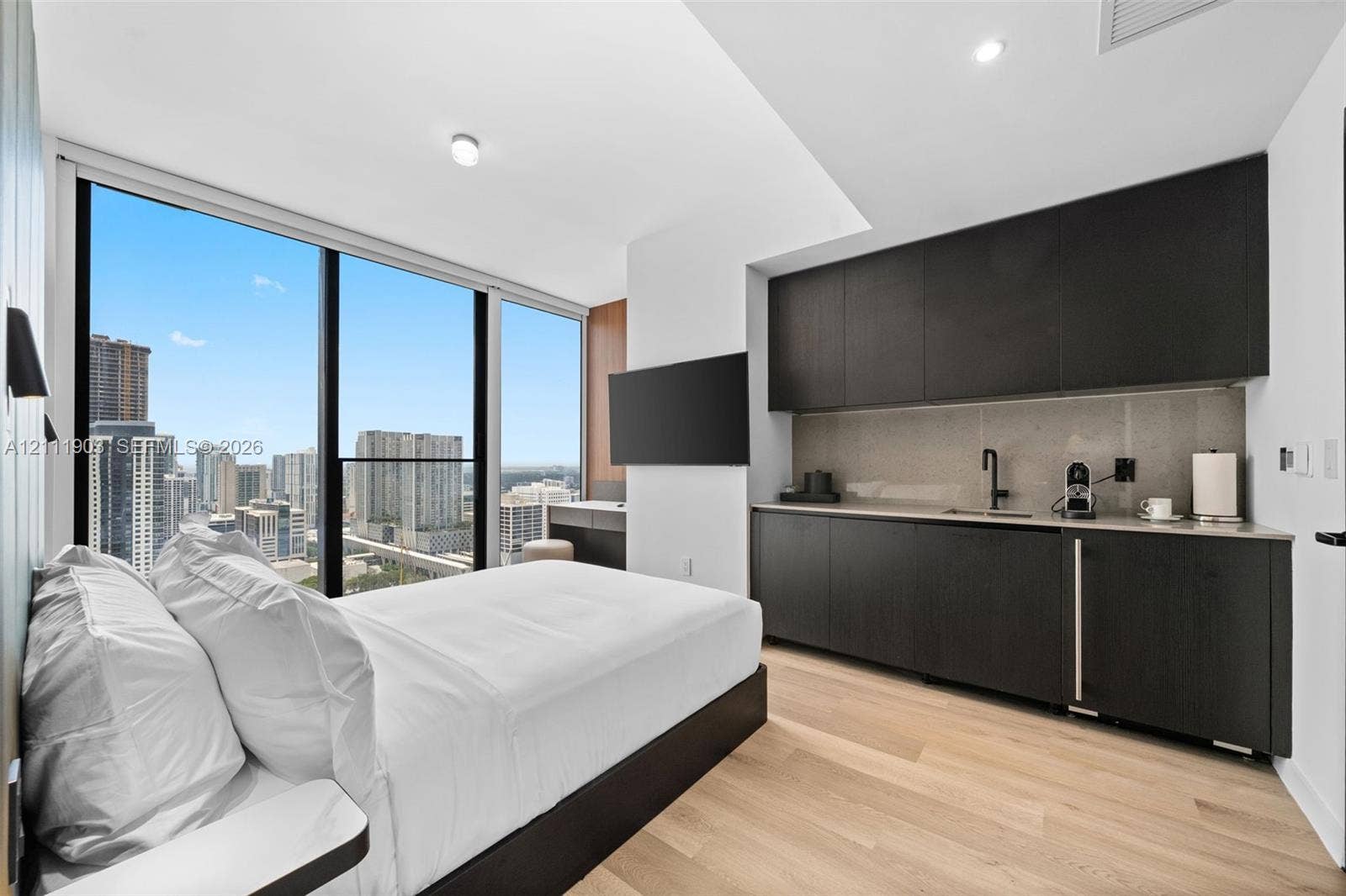 20 NE 11th Street, #4308, Miami, FL 33132 Floor-to-ceiling windows, wood-finish flooring, custom dark cabinetry, stone-finish backsplash, and recessed lighting