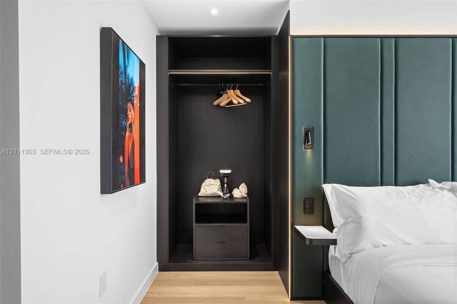 20 NE 11th Street, #4308, Miami, FL 33132 Built-in wardrobe with dark cabinetry, upholstered green vertical-paneled accent wall, recessed lighting, and wood-finish flooring