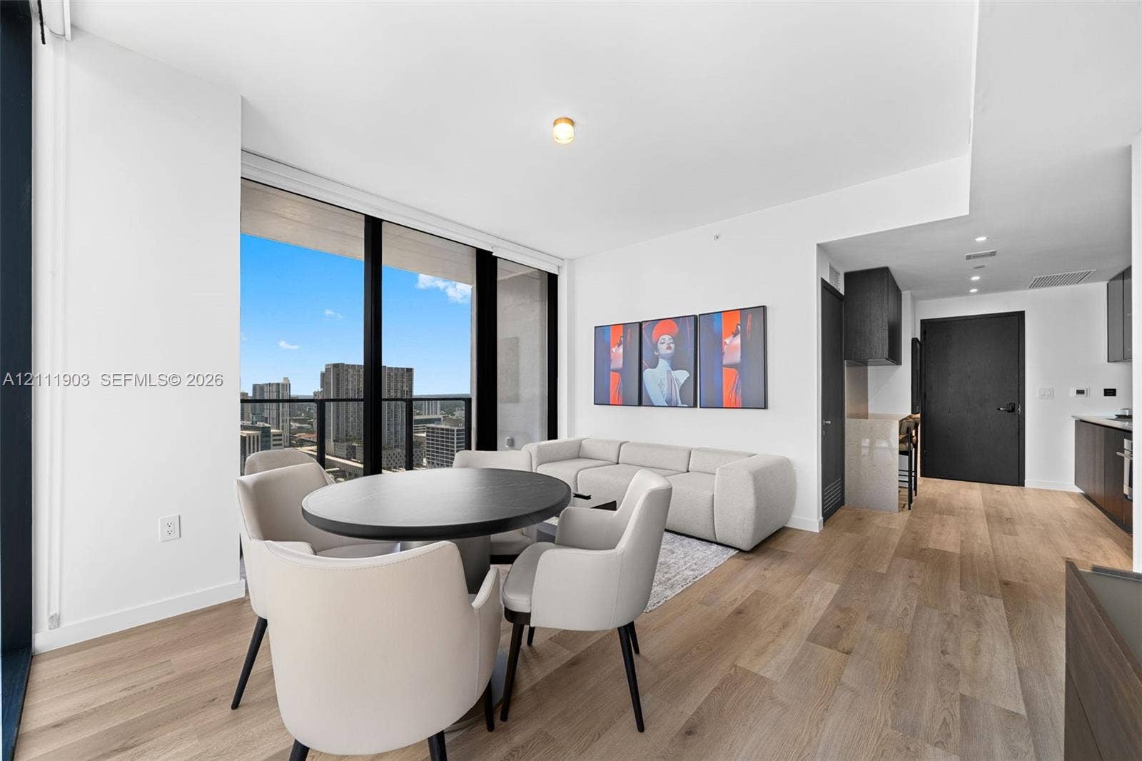 20 NE 11th Street, #4308, Miami, FL 33132 Open-concept living space featuring floor-to-ceiling windows, wood-finish flooring, and a kitchen with dark cabinetry and stone countertops