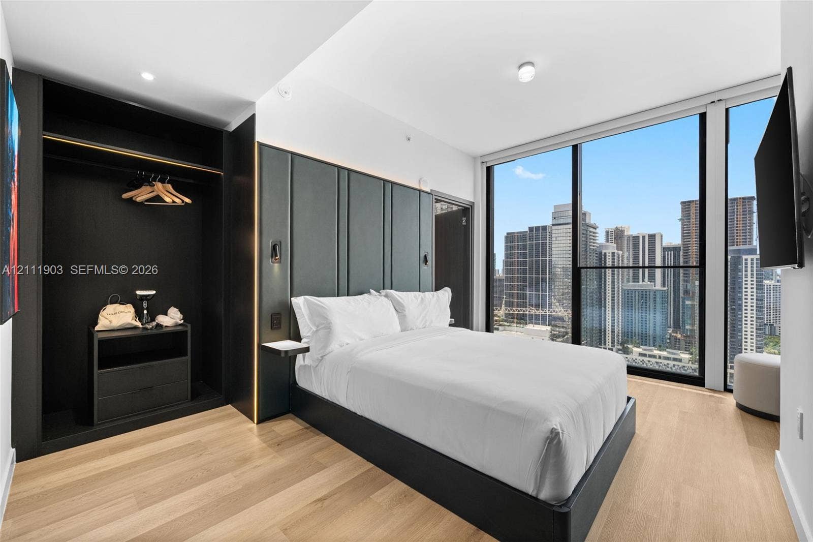 20 NE 11th Street, #4308, Miami, FL 33132 Floor-to-ceiling windows with urban skyline exposure, wood-finish flooring, built-in open-concept wardrobe with integrated storage, and decorative wall paneling with mounted accent lighting