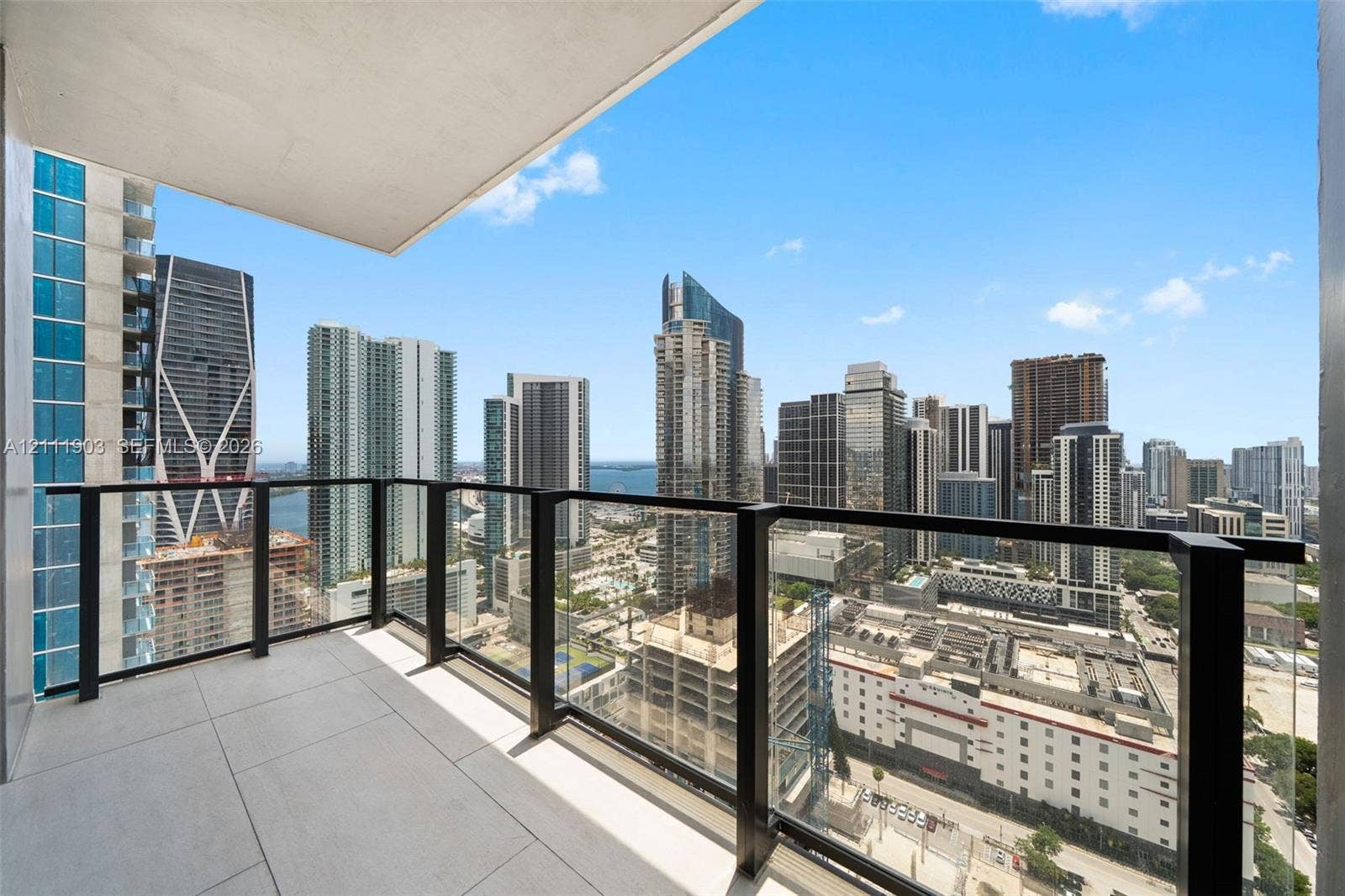20 NE 11th Street, #4308, Miami, FL 33132 Covered balcony featuring large-format ceramic floor tiles and a minimalist black metal railing with glass panels